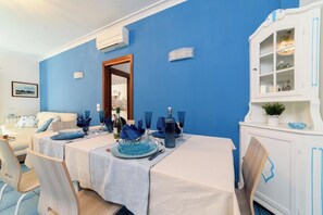 Ein Essbereich mit blauer Wand, weißen Möbeln und einem weißen Schrank mit Glastüren.