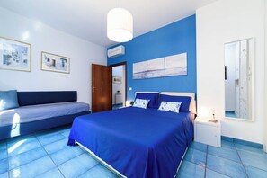 Ein Schlafzimmer mit einem großen Bett, einem kleinen Sofa, einem Nachttisch und einem Spiegel.