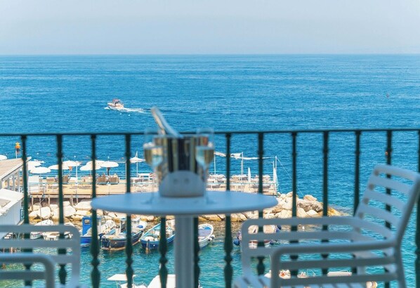 A balcony with a table and chairs overlooking a marina with boats and a pier. - Casa Mareluna, Elegance in the Heart of Sorrento (Sorrento)