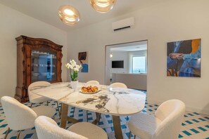 A dining area with a marble table, white chairs, a large wooden cabinet, and a potted orchid. - Casa Mareluna, Elegance in the Heart of Sorrento (Sorrento)