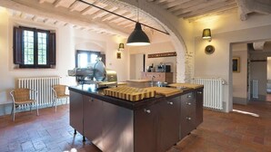 Una cocina con una isla central, suelo de ladrillo rústico y vigas de madera a la vista en el techo.