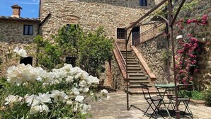 A stone building with a staircase leading to an upper level, surrounded by white flowers and greenery. - Villa Armonia, Tranquillity with Panoramic Views (Larciano)