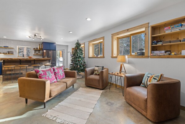 A modern living room with leather sofas, a coffee table, and a Christmas tree. - Indoor Basketball Court, Hot Tub & Billiards - 5 Acres, Pet-Friendly (Fairplay)