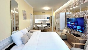 A modern hotel room with a large bed, a TV, a dining area, and a kitchen. - Apartment - 85 sqm - Grenelle - 8p (Paris)