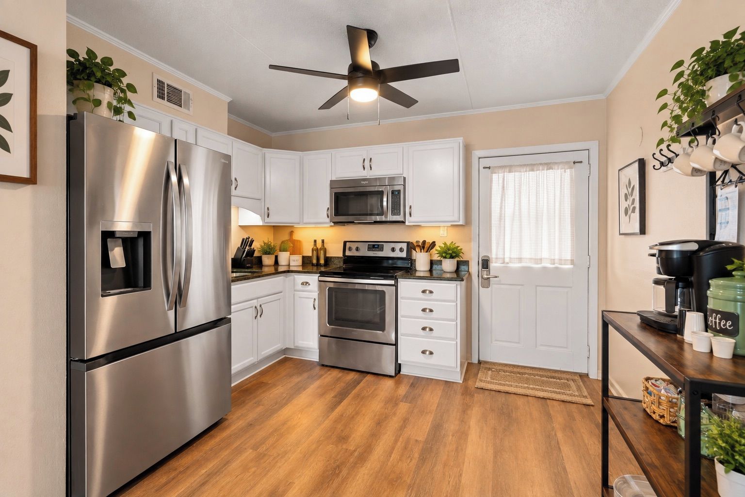 A modern kitchen with stainless steel appliances, white cabinetry, and a ceiling fan.