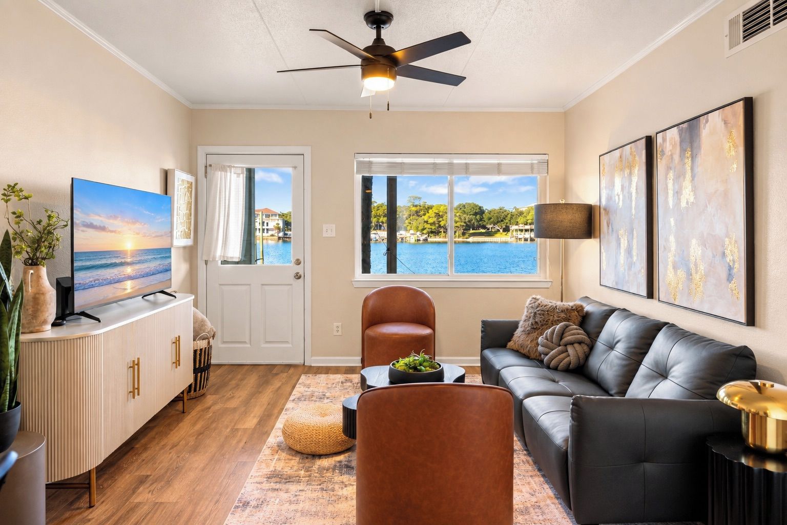 A modern living room with a view of a lake, a ceiling fan, and a flat-screen TV.