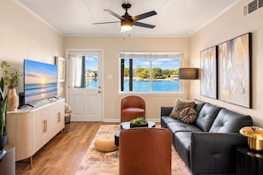 Un salon moderne avec vue sur un lac, doté d’un ventilateur de plafond et d’un téléviseur à écran plat.