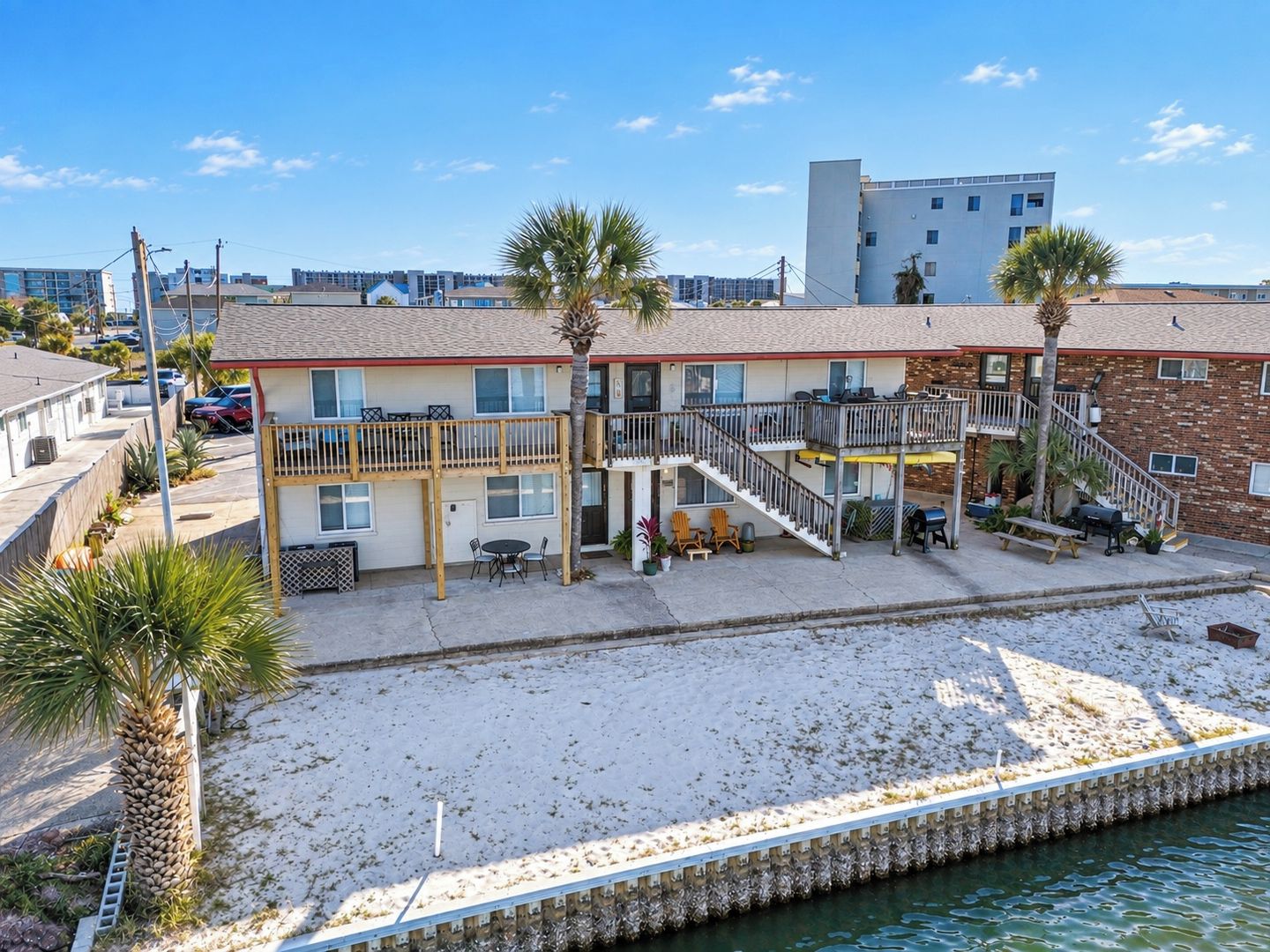 A beachfront hotel with a balcony, outdoor seating, and a poolside area.