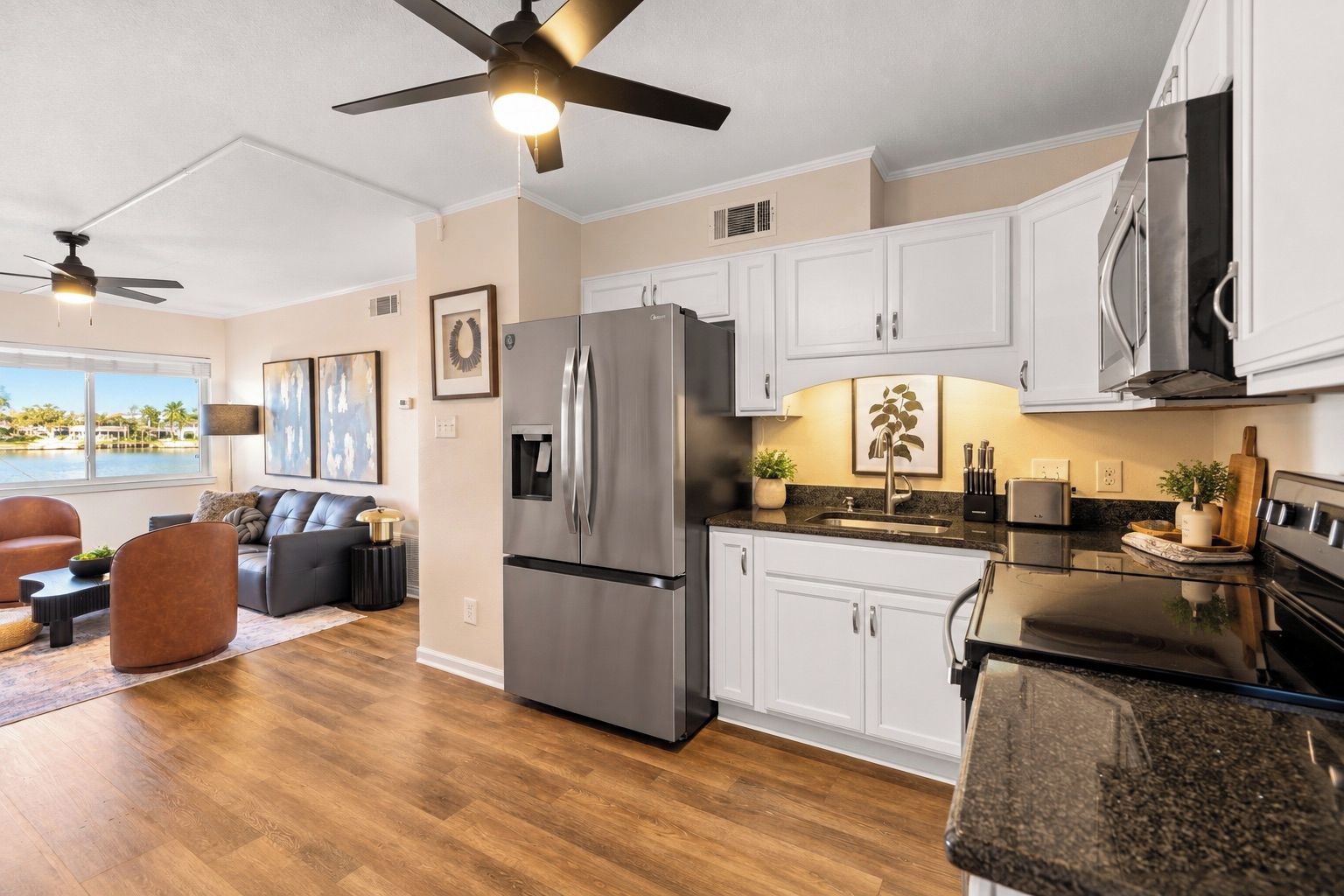 A modern kitchen with white cabinets, stainless steel appliances, and a dining area with a dark countertop.