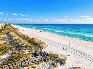 A beach with a wooden boardwalk and a pier in the distance. - Dockside Daydream Waterfront Next-To-Beach (Fort Walton Beach)
