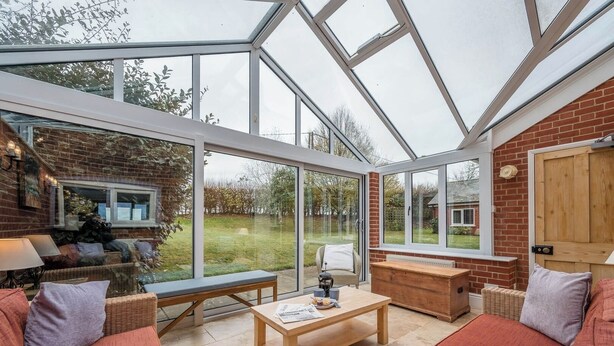 A conservatory with a glass roof, furnished with a sofa, a table, and a bench. - 1 Box Iron Cottage, Shotley (Shotley)