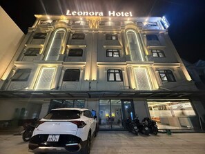 La façade de l’hôtel Leonora, avec une voiture blanche garée devant.