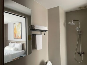 A modern bathroom with a bed, a shower, and a towel rack. - Leonora Hotel (Phuong an Nhon)