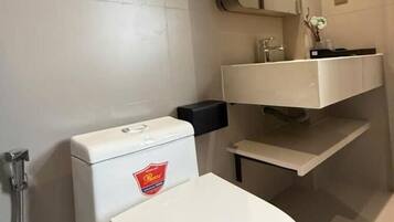 Un baño moderno con inodoro, lavamanos y espejo.