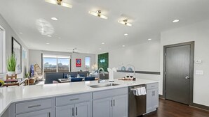 Una cocina moderna con una isla grande, gabinetes grises y vistas a la ciudad.