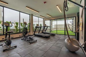 Ein Fitnessraum mit Laufbändern, Crosstrainern und Kurzhanteln.