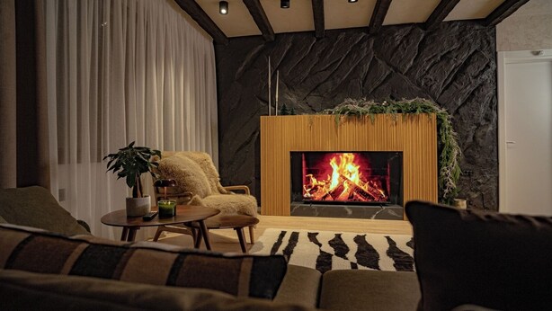 A cozy living room with a fireplace, a plush armchair, a coffee table, and a sofa. - The Pines Chalet w. free parking (Brașov)