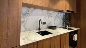 A modern kitchen with wooden cabinets, a marble backsplash, a black faucet, and a black pot on the counter. - The Pines Chalet w. free parking (Brașov)