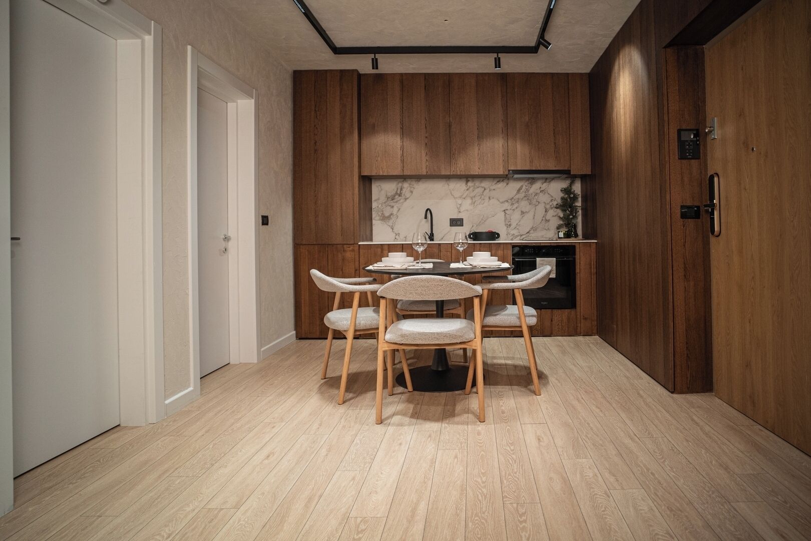 Una cocina moderna con armarios de madera, un protector contra salpicaduras de mármol y una zona de comedor con una mesa y sillas.