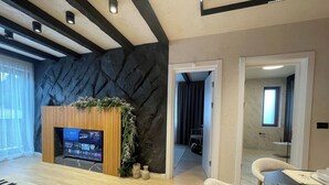 A modern living room with a fireplace, a television, and a dining area with a table and chairs. - The Pines Chalet w. free parking (Brașov)