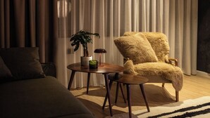A modern living room with a sofa, a round wooden table with a plant and candle, and a fluffy armchair. - The Pines Chalet w. free parking (Brașov)