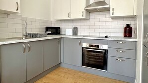 A modern kitchen with grey cabinets, a microwave, a toaster, and an oven. - Shoreditch Apartments by PrimeCityHosts F3 (Greater London)