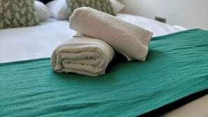 A neatly made bed with a green bedspread, white pillows, and a folded towel on top. - Shoreditch Apartments by PrimeCityHosts F3 (Greater London)