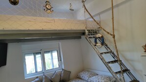 Ein Zimmer mit einem Bett, einem Fenster, einer Leiter und einer Wanduhr.