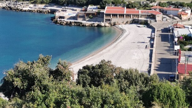Eine Küstenstadt mit Sandstrand, einer Marina und Gebäuden mit roten Dächern.