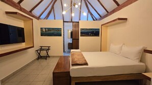Un dormitorio con cama, televisor y obras de arte en las paredes.