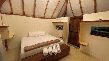 A bedroom with a wooden bed frame, a white mattress, and two rolled towels.