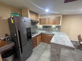 Una cocina con refrigerador, estufa, lavadero y armarios de madera.