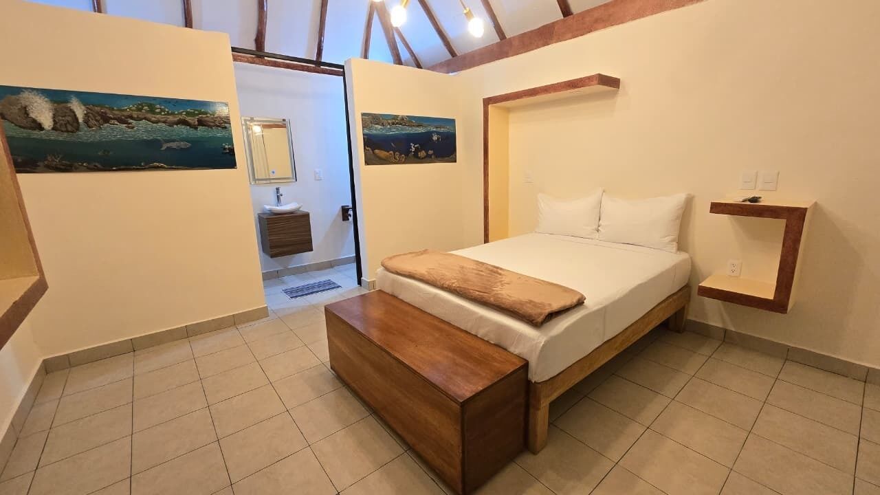 Ein Schlafzimmer mit einem Bett, einer Holzbank, einem Nachttisch und zwei Bildern an den Wänden.