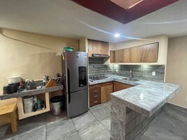 Eine Küche mit Kühlschrank, Spüle und Holzschränken.