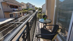 A balcony with a table and two chairs, overlooking a street with houses and a clear sky. - Studio-Apartment mit Balkon by Interhome (Tivat)