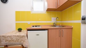 A compact kitchen with yellow tiles, a sink, a stove, and a refrigerator. - Studio-Apartment mit Balkon by Interhome (Tivat)