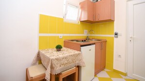 A compact kitchen with a sink, a small refrigerator, and a table with a lace tablecloth. - Studio-Apartment mit Balkon by Interhome (Tivat)