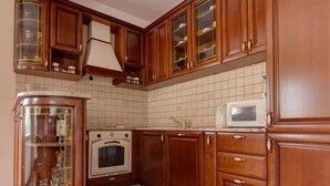 Eine Küche mit Holzausstattung, einem eingebauten Backofen und einer Mikrowelle.
