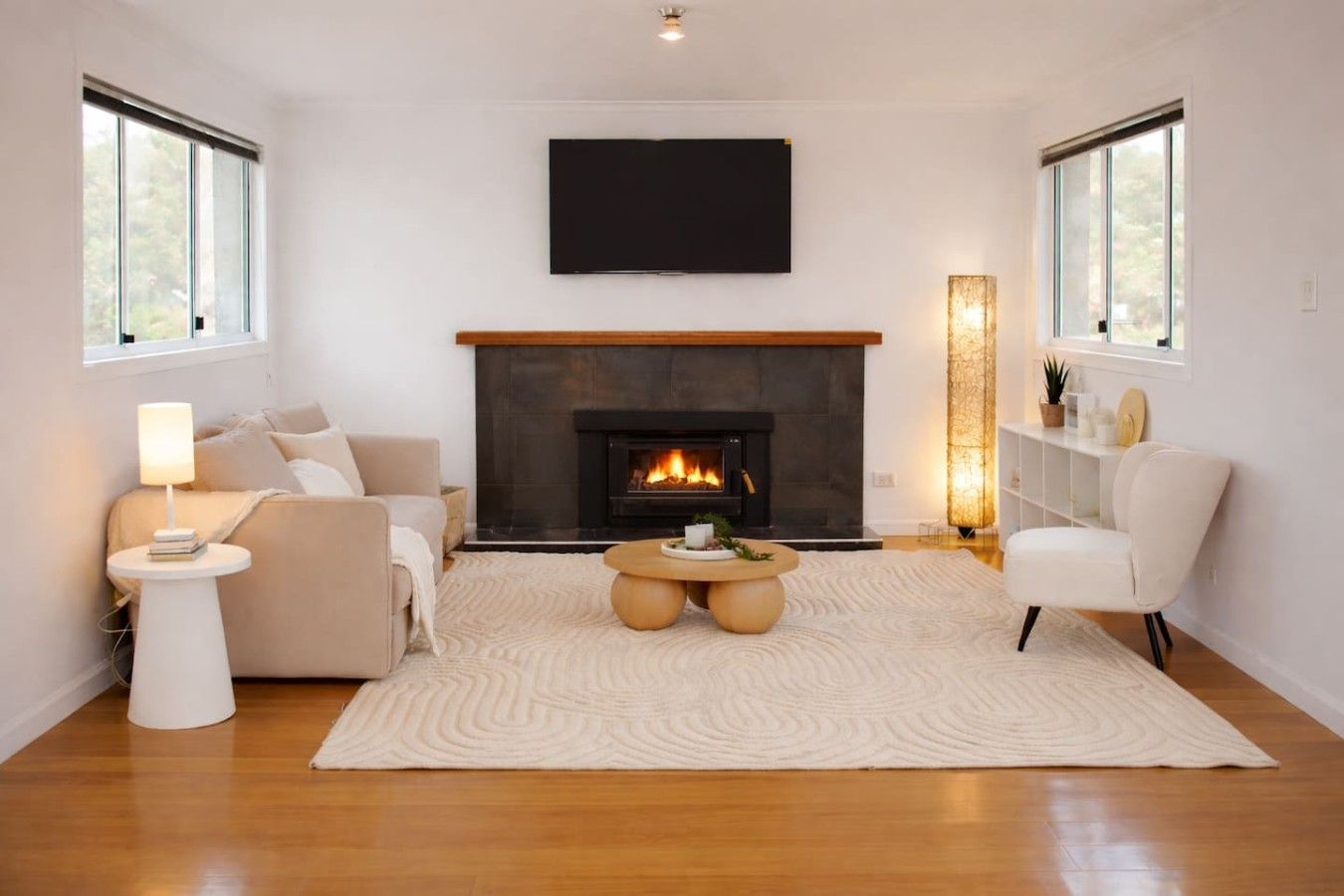 A modern living room with a fireplace, a sofa, a coffee table, and a TV mounted on the wall.