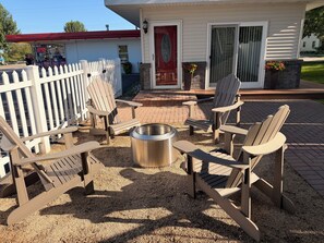A patio area with Adirondack chairs, a fire pit, and a white picket fence. - Marina House - Lake Life and Shirley's Treats Next Door (Starbuck)