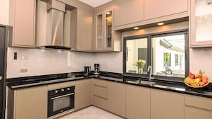 Een moderne keuken met inbouwapparatuur, een groot raam en uitzicht op buiten.