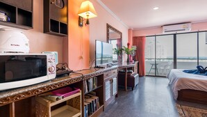 Une chambre d’hôtel équipée d’une kitchenette, d’un lit, d’une grande fenêtre avec vue et d’un miroir.