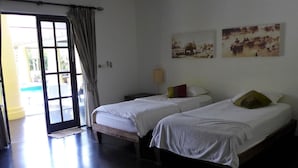 Ein Hotelzimmer mit zwei Betten, einer zur Balkontür und zwei an der Wand befestigten Bildern.