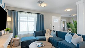Een moderne woonkamer met een modulaire bank, een rond bijzettafeltje en een televisie.