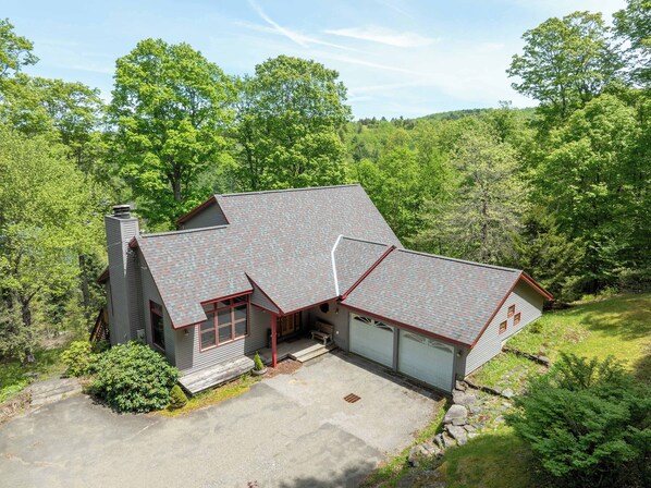 A two-story house with a sloped roof, a garage, and a driveway.