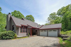 A two-story house with a garage, a chimney, and a front porch.