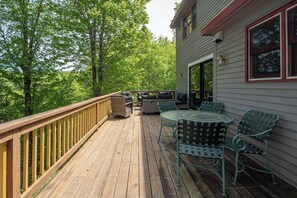 A wooden deck with outdoor furniture, a railing, and a house with a window.