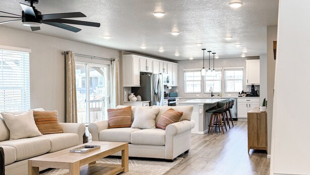 Un salón amplio con sofá, mesa de centro y ventilador de techo.