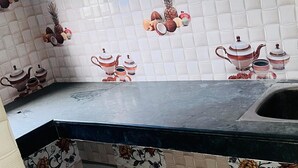 A kitchen with white patterned tiles, a black countertop, and decorative tiles with geometric and floral designs.