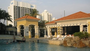 A swimming pool area with lounge chairs and a building with a tiled roof. -  Mantra Towers of Chevron Holiday in Paradise (Surfers Paradise)